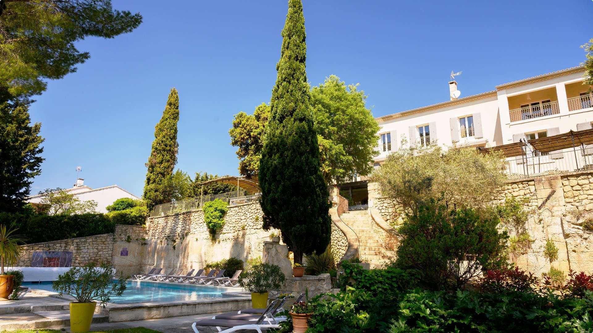 Vue sur l'espace piscine et la façade Hôtel Fontvieille, Le Belesso