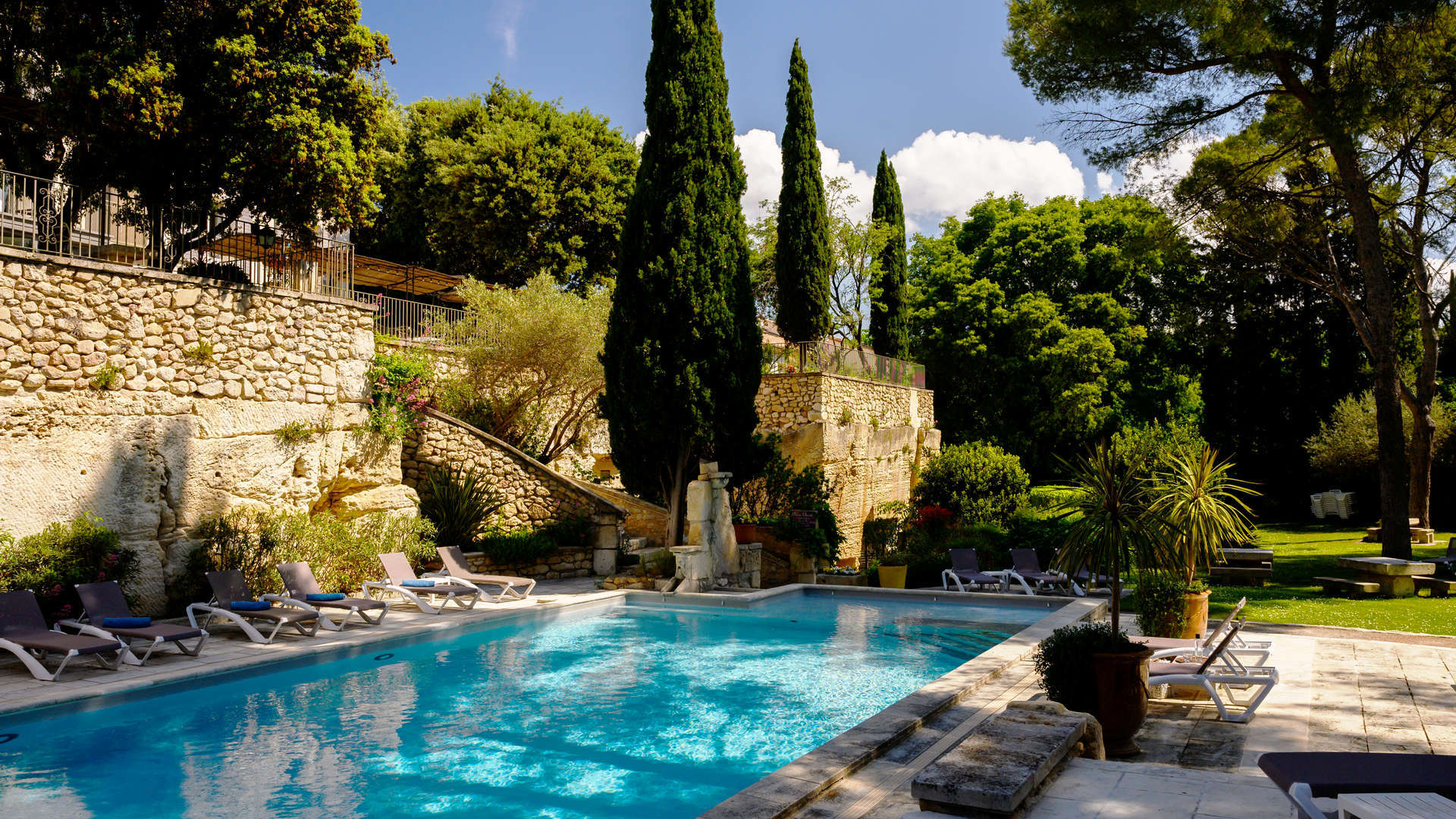 Vue de profil sur la piscine et son environnement qui l'entoure - Hôtel Fontvieille, Le Belesso