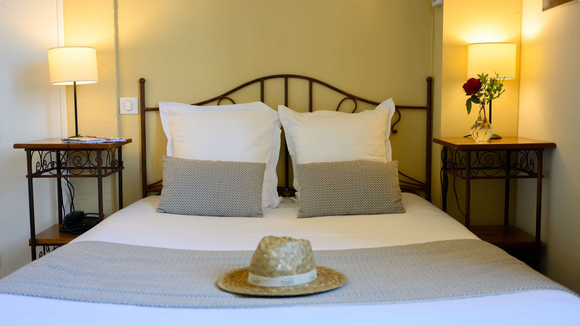 Chambre avec lit double avec un chapeau dessus - hotel fontvieille - Belesso
